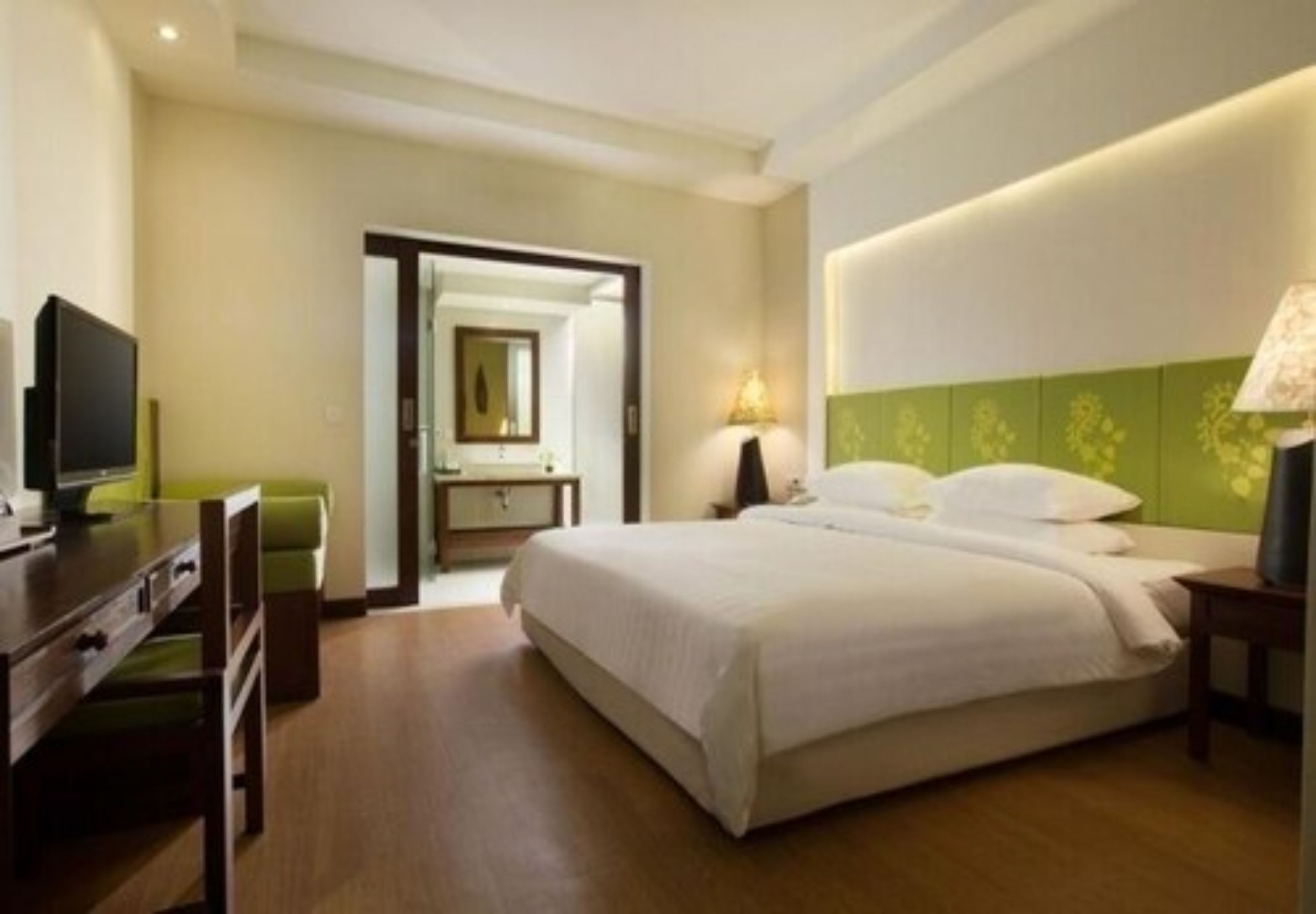 Een hotelkamer met een bed, een bureau, een stoel, een televisie en een lamp.