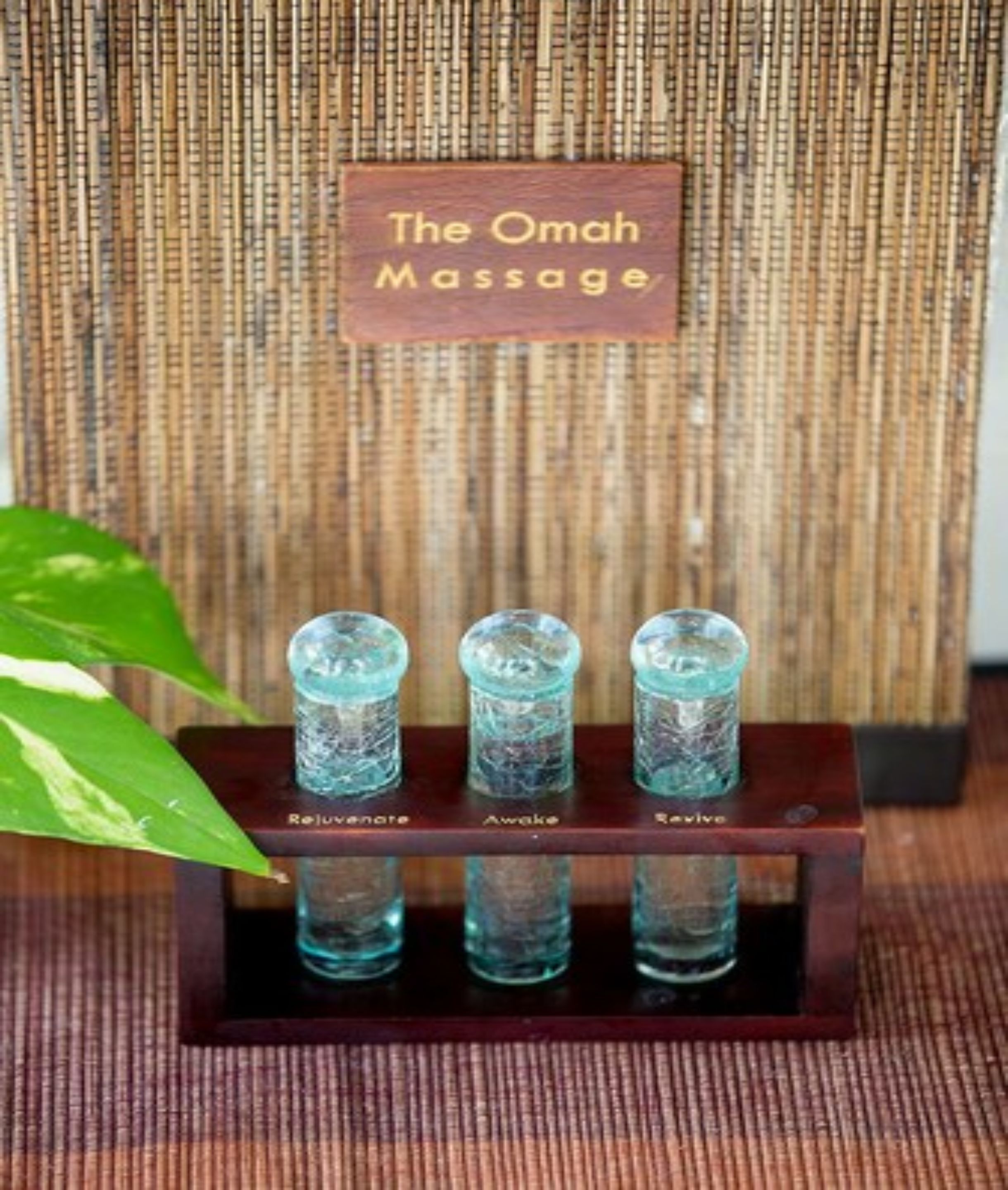 A wooden stand with three glass bottles labeled "Relaxation," "Awake," and "Revive" at The Omaha Massage.