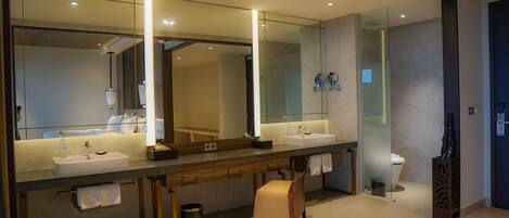 A modern bathroom with two sinks, a large mirror, and a glass shower enclosure.