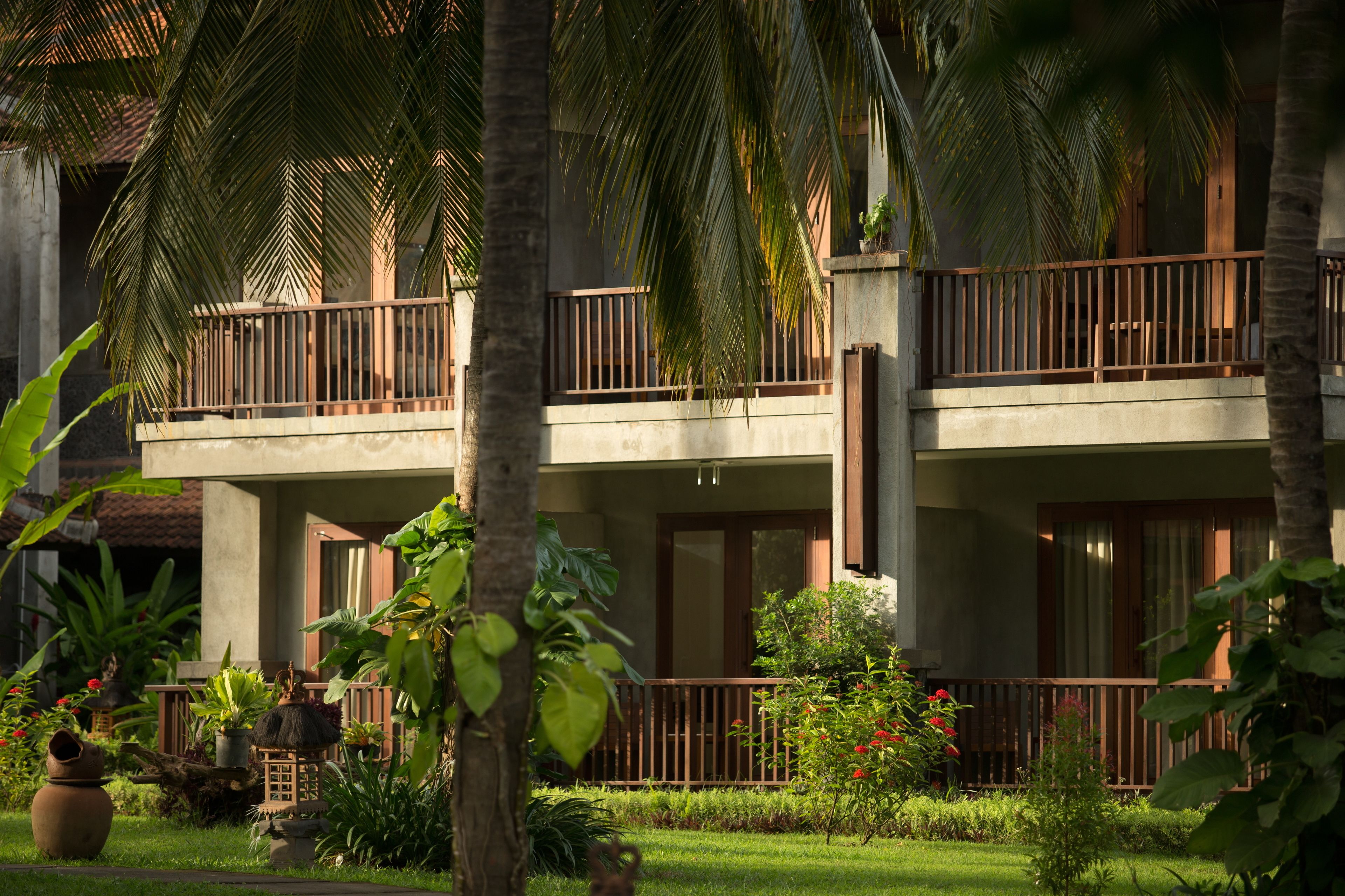 A hotel with a two-story structure, balconies, and lush tropical landscaping.