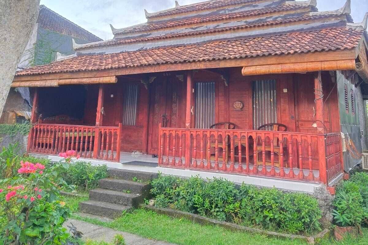 A traditional building with a tiled roof, a red facade, and a wooden balcony.