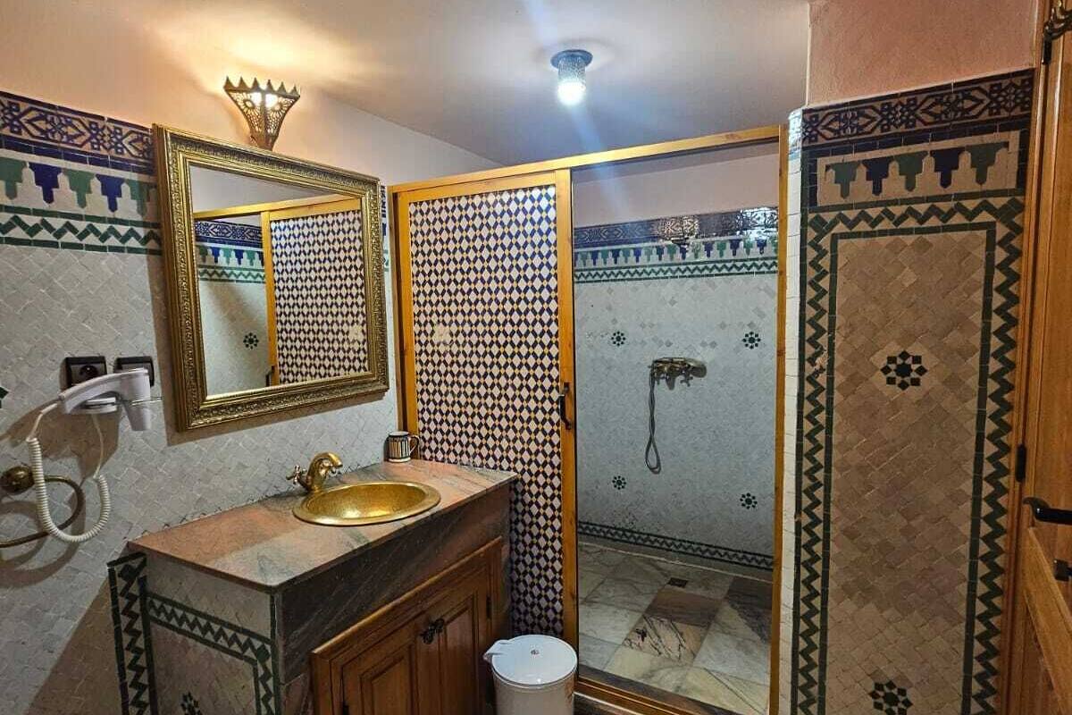 A bathroom with a sink, mirror, toilet, and shower area.
