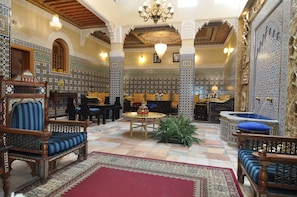 A traditional interior with ornate tile work, a chandelier, and classic furniture.