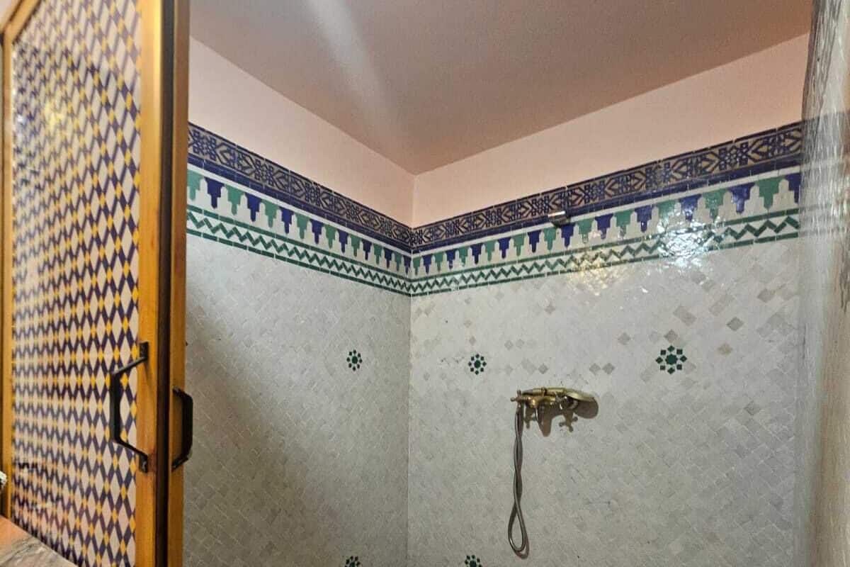 A bathroom with patterned tiles, a shower, and a tiled floor.
