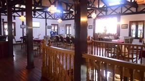 A spacious room with wooden beams, a balcony, and a Buddha statue.