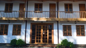 A two-story building with a balcony, wooden doors, and windows.
