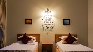 A hotel room with two beds, a nightstand, and a motivational quote on the wall.