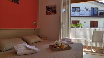 A bedroom with a bed, pillows, a tray with food and drinks, a chair, and a balcony with a railing.