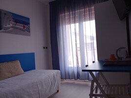 Un dormitorio con cama, escritorio y ventana con cortinas.