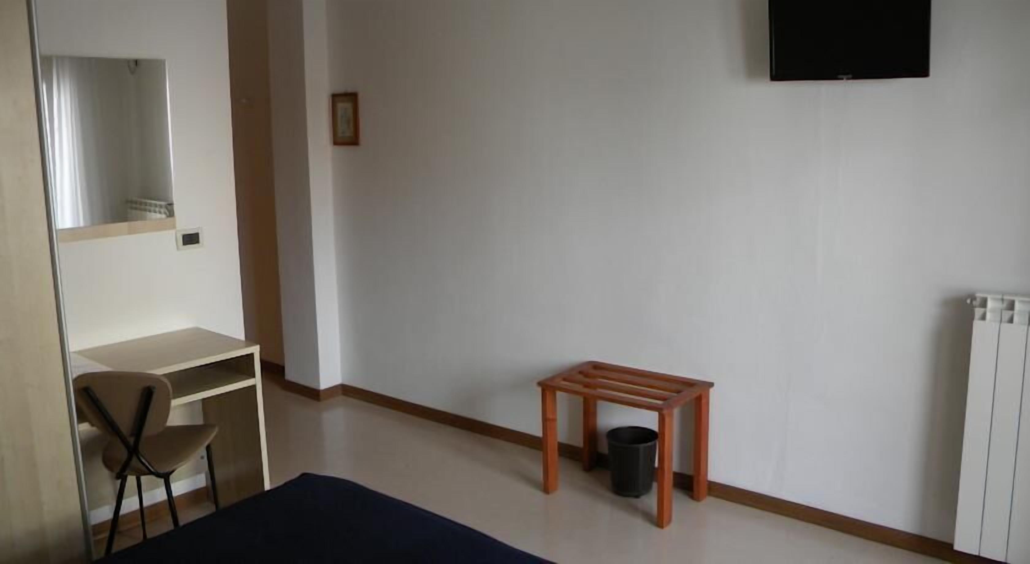 Une pièce comprenant un bureau, une chaise, une petite table et un radiateur.