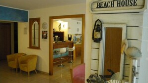 Ein Zimmer mit Fliesenboden, Holzmöbeln, einer Bar und einem Schild mit der Aufschrift 'Beach House'.