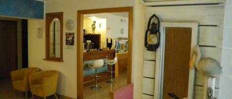 A room with a tiled floor, wooden furniture, a bar area, and a 'Beach House' sign.