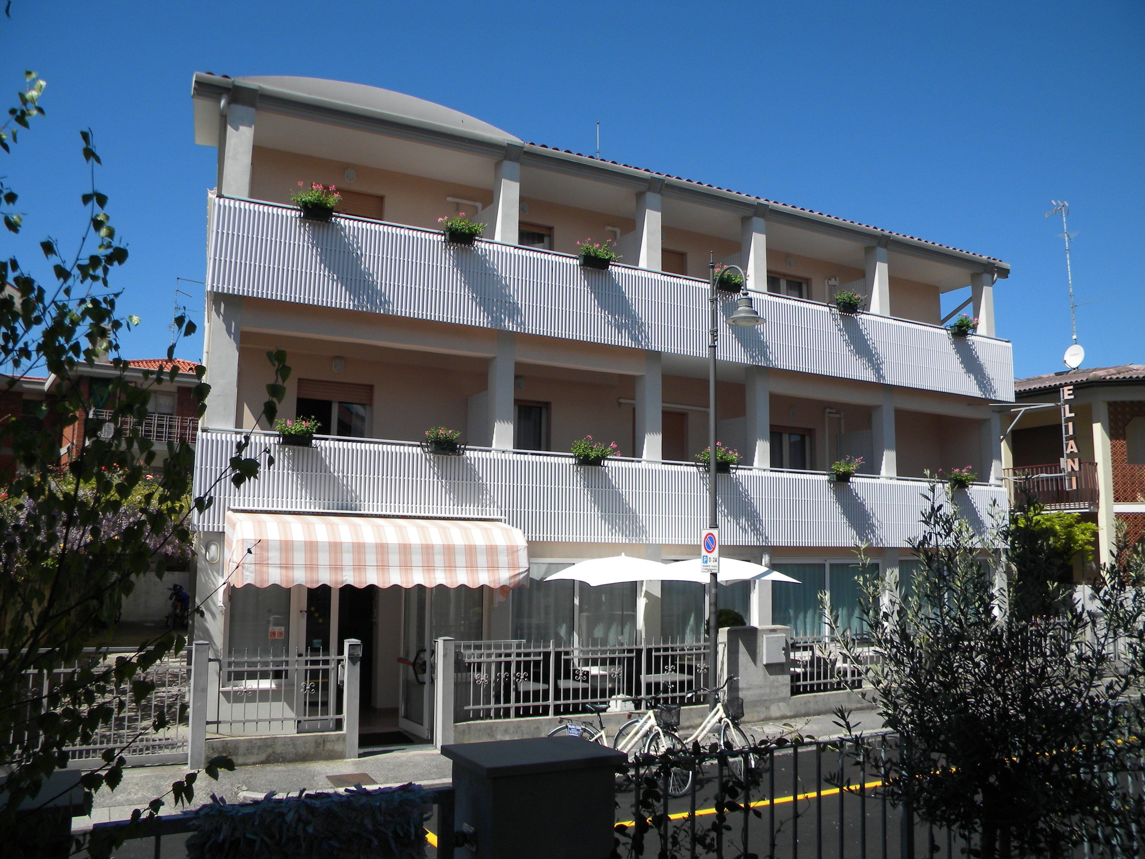 Un hotel de varios pisos con balcones, una entrada cubierta y un cartel que indica que no se permite el estacionamiento.