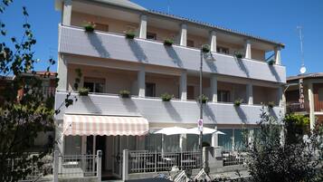 Un hotel de varios pisos con balcones, una entrada cubierta y un cartel que indica que no se permite el estacionamiento.