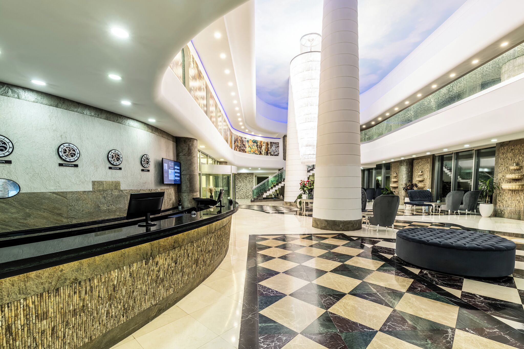 Un hall de hotel con mostrador de recepción, zona de estar y una escalera que lleva a los pisos superiores.