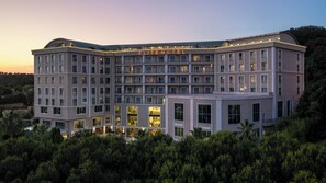 Un hôtel à plusieurs étages, reconnaissable à son grand panneau « HÔTEL ELITE », à ses grandes fenêtres et à son espace paysager agrémenté de verdure.