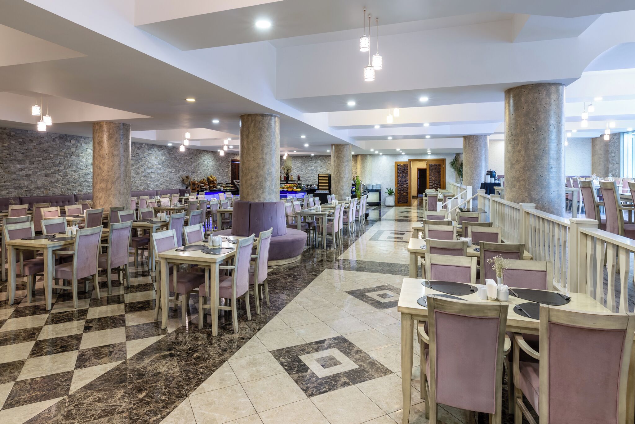 Un restaurante espacioso con varias zonas de comedor, paredes de piedra y un suelo con estampado de cuadros.