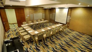 A conference room with a long table, chairs, a projector screen, and a carpeted floor. - Elite Hotel Darica (Darica)
