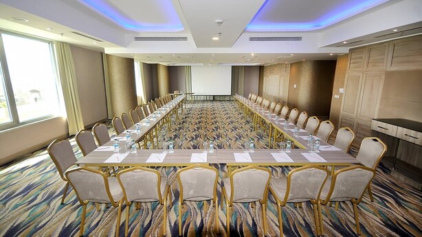 Une salle de conférence équipée d’une longue table, de chaises et d’un écran de projection.