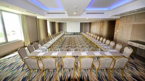 A conference room with a long table, chairs, and a projector screen. - Elite Hotel Darica (Darica)