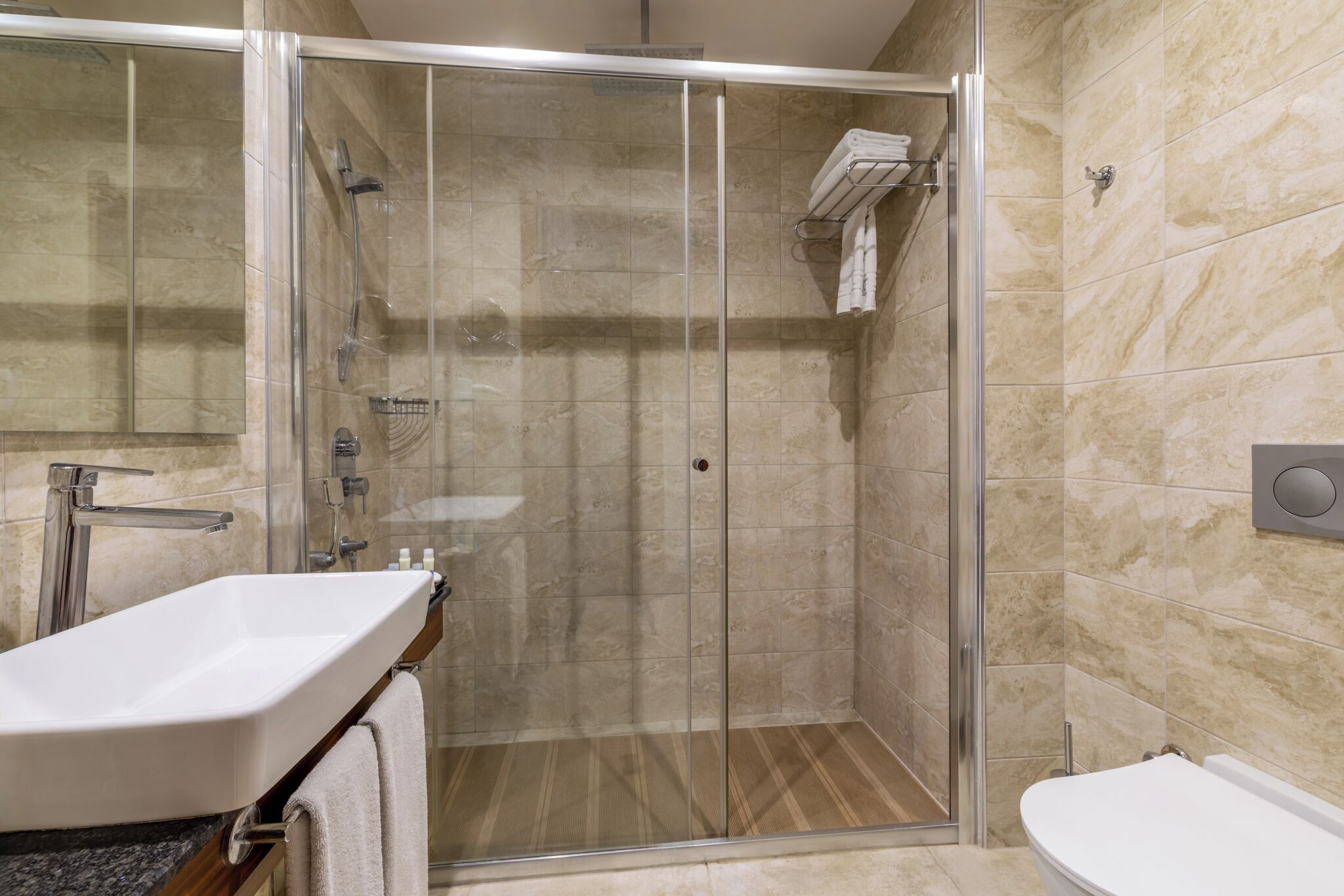 Un baño moderno con ducha de vidrio, lavamanos e inodoro.