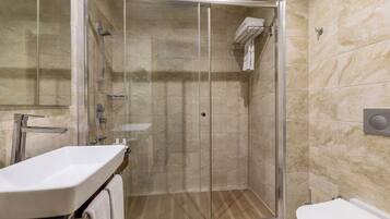 Un baño moderno con ducha de vidrio, lavamanos e inodoro.
