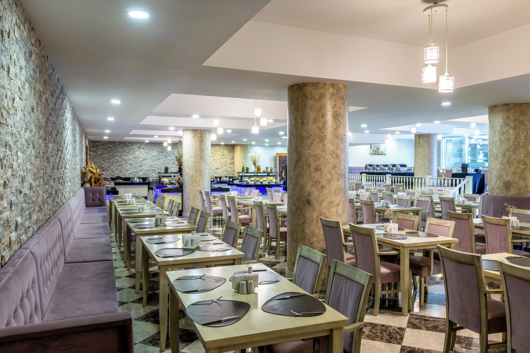 Um restaurante com várias mesas e cadeiras, uma área de bar e uma parede de pedra.
