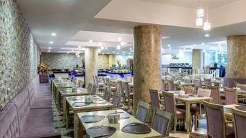 Um restaurante com várias mesas e cadeiras, uma área de bar e uma parede de pedra.