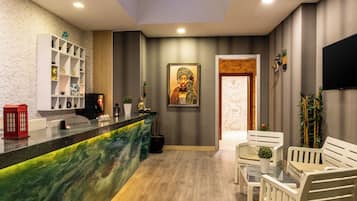 A reception area with a marble counter, a Buddha statue, and a reception desk.