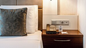A hotel room with a bed, a nightstand, a lamp, and a phone.