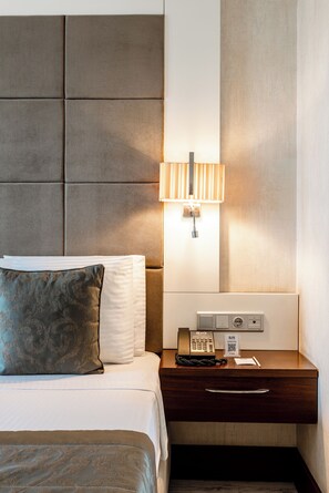 A hotel room with a bed, a nightstand, a lamp, and a phone.