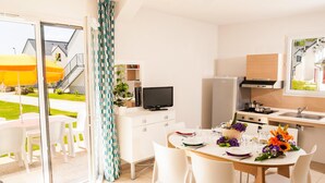 Cozinha moderna com área de refeições, televisão e vista para o exterior.