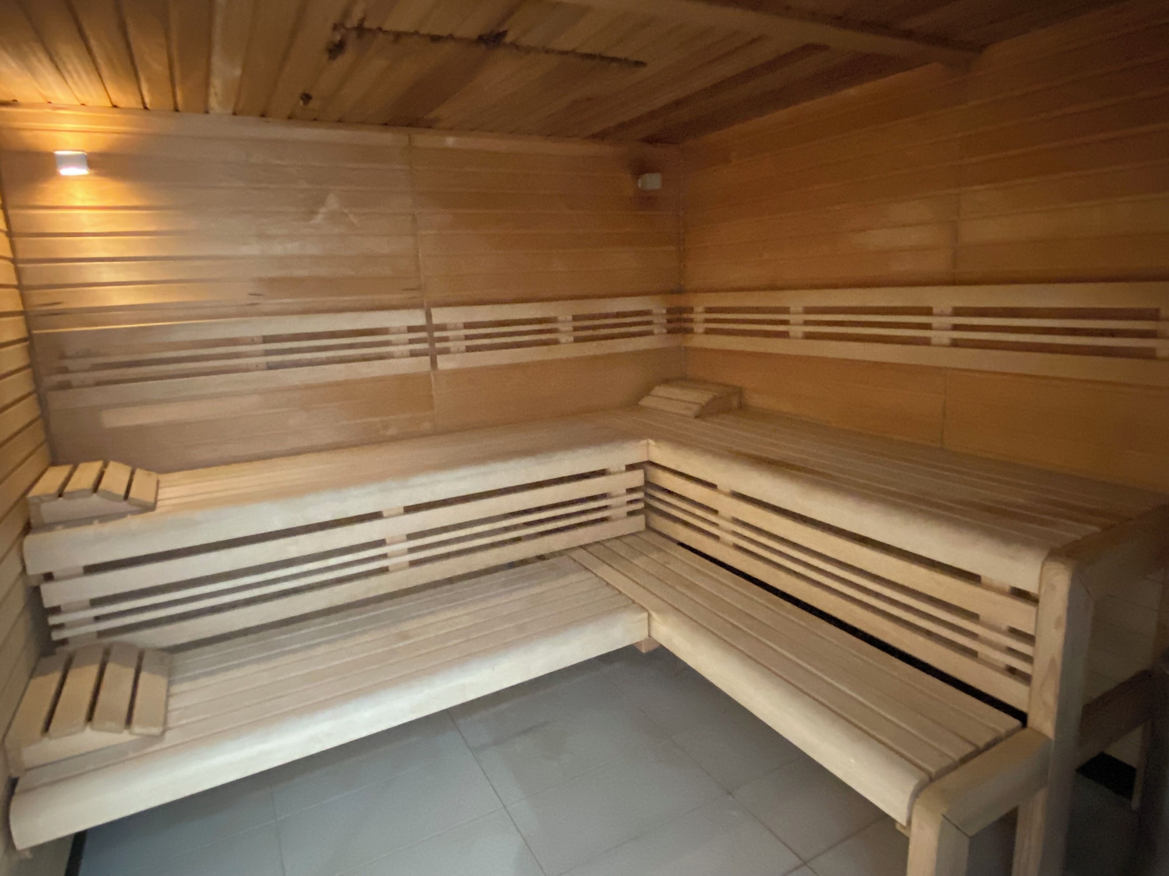 Una sauna con bancos de madera, piso inclinado y techo con vigas de madera.