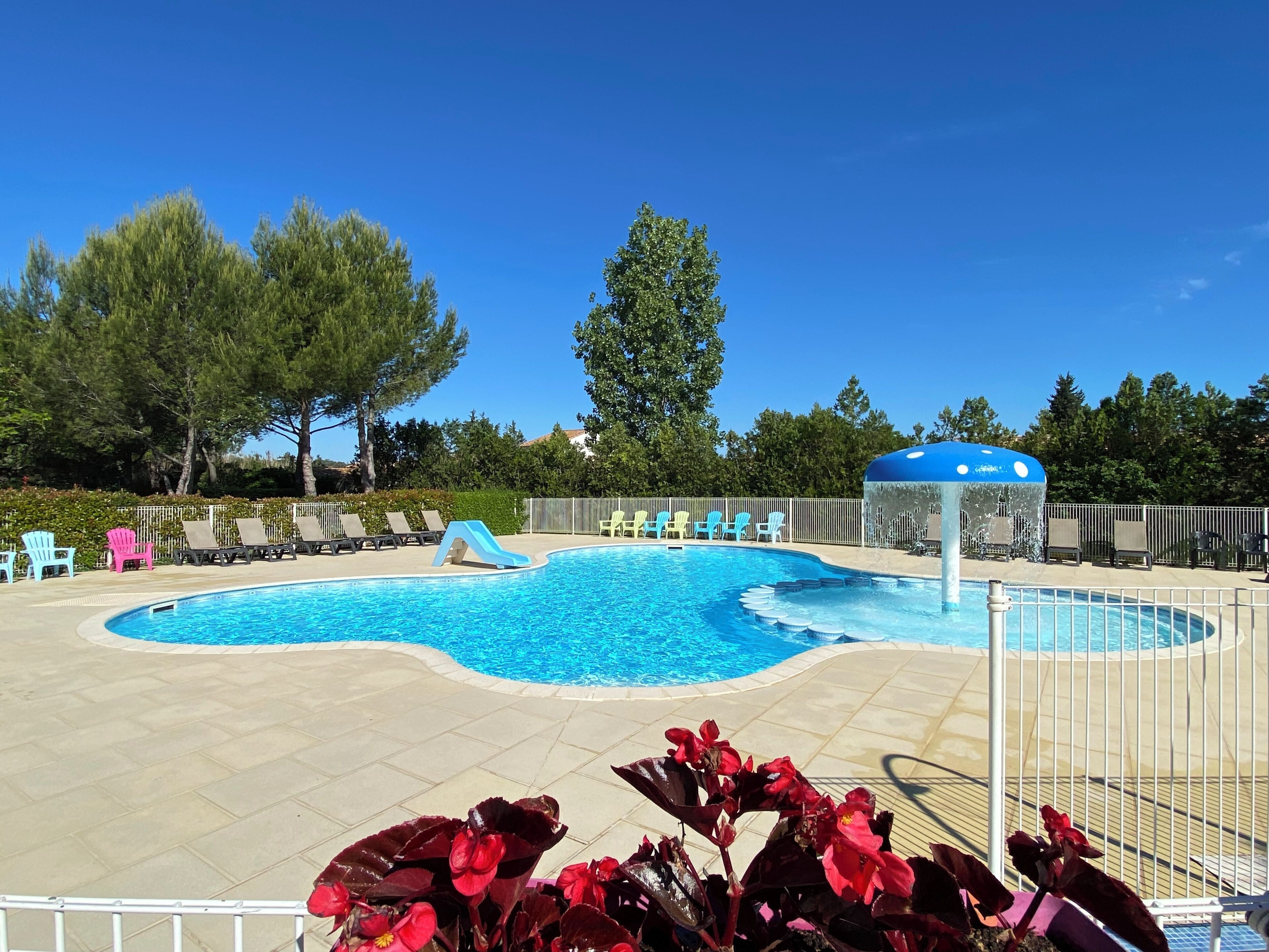 Una piscina con sillas de descanso y una fuente.
