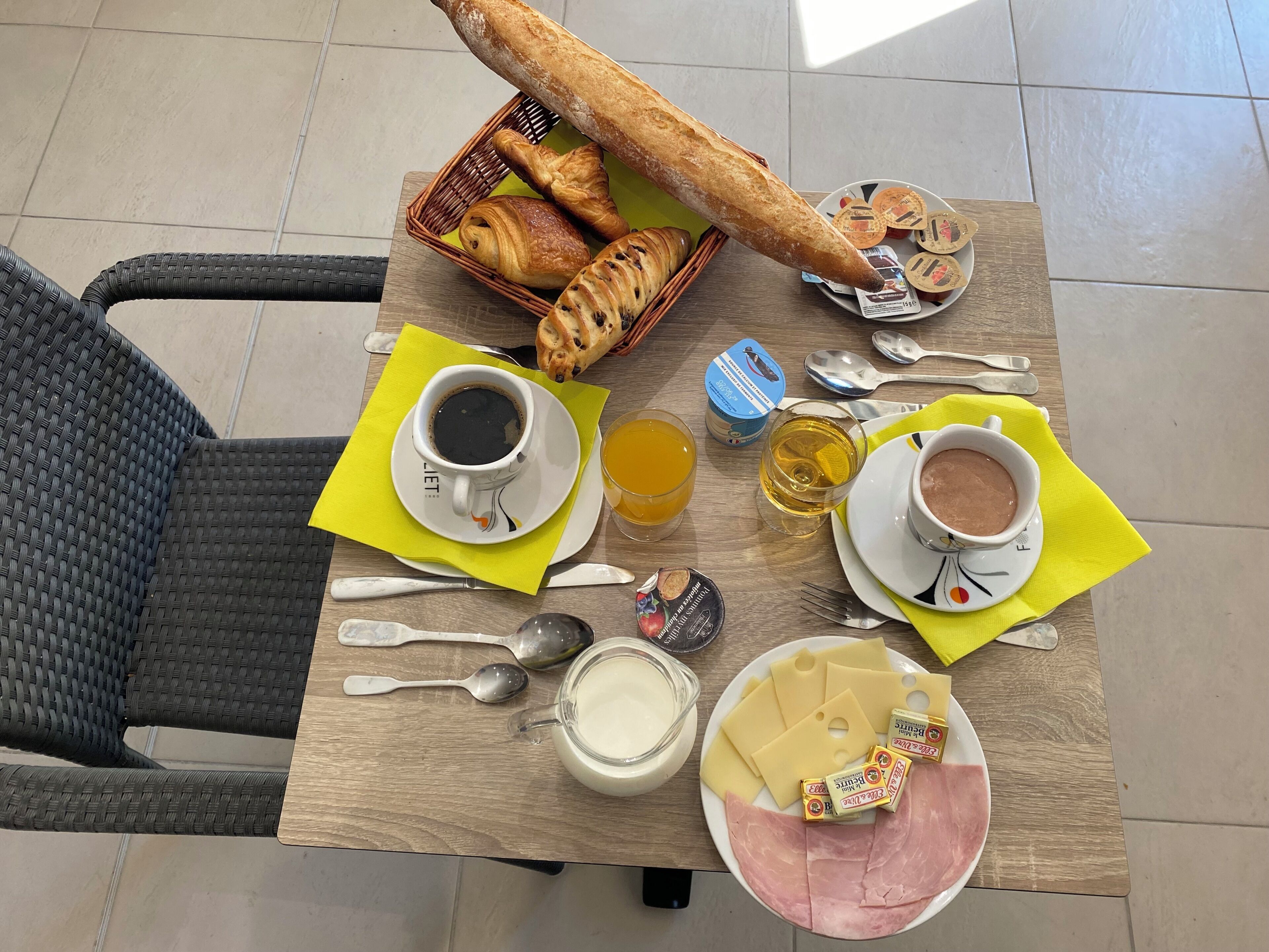 Una tavola imbandita con pane, pasticcini, caffè, succo d'arancia e formaggio.