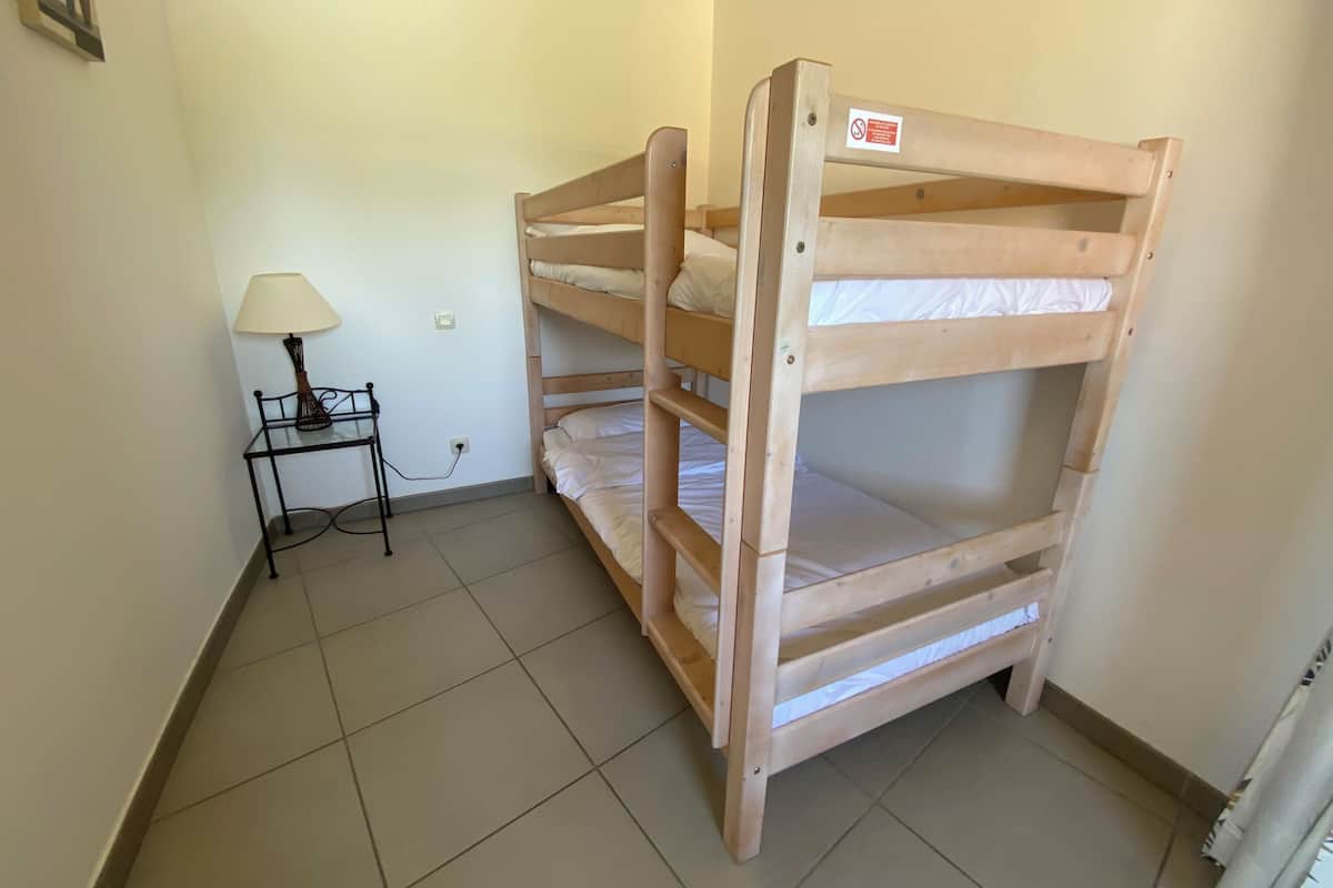 A bunk bed room with a small table and lamp.
