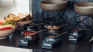 A buffet with various food items including a bowl of fruit, bowls of nuts, and jars of dried berries and almonds. - Geo Hotel Grindavik (Grindavik)