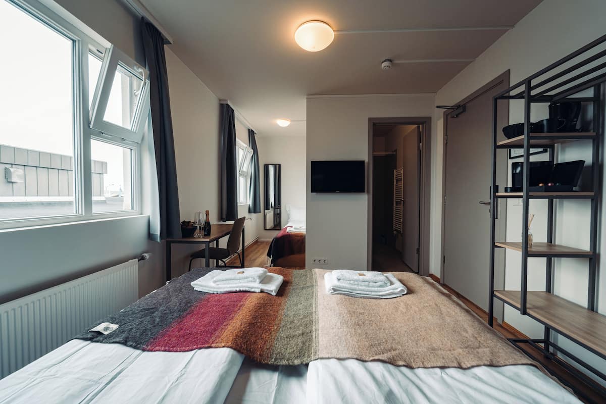 A modern hotel room with two beds, a TV, a desk, and a wardrobe.