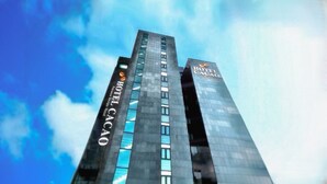 A tall building with the Hotel Cacao sign, featuring a modern glass facade and a prominent logo at the top. - Sorae Tourist Hotel Cacao (Incheon)