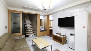 A modern living room with a sofa, a coffee table, a TV, and a built-in heater. - Sorae Tourist Hotel Cacao (Incheon)
