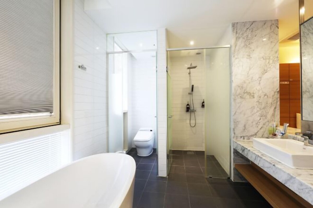 A modern bathroom with a freestanding bathtub, a glass-enclosed shower, and a marble-tiled vanity.