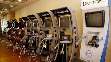 Uma fileira de estações de jogos Nintendo GameCube com cadeiras e um console Dreamcast.