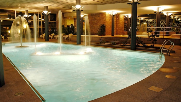 Una piscina con diversas fuentes y zonas de estar.