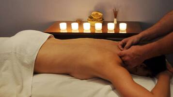 Sessão de massagem com velas sobre uma mesa.