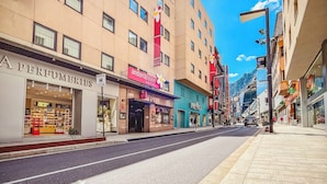 Una calle con un hotel llamado Andorra Palace Hotel, una tienda llamada Perfumeries, y un edificio con un cartel que indica Prestig.