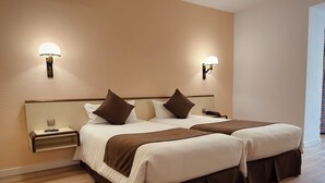 Una cama doble con dos mesitas de noche, cada una con una lámpara y un teléfono.
