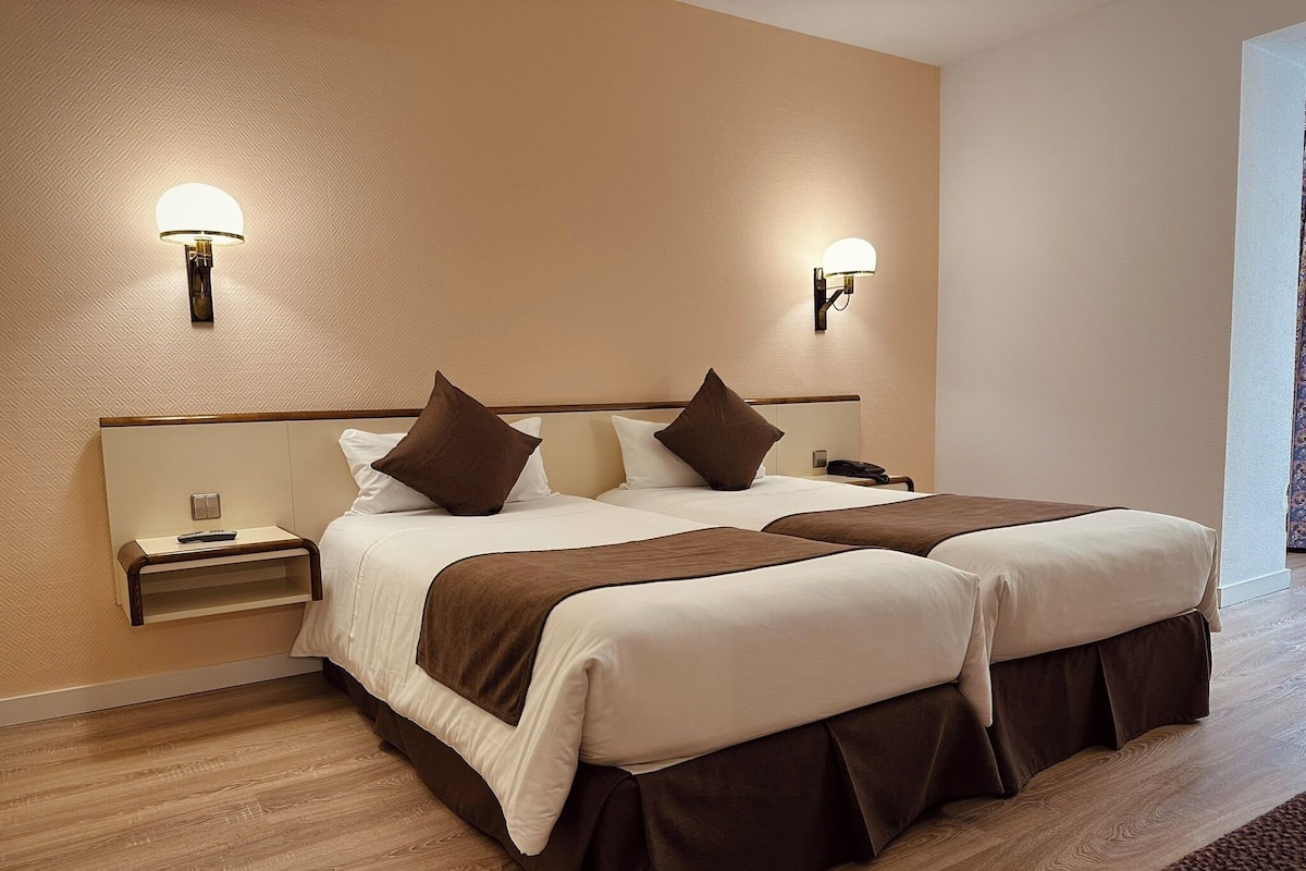 A double bed with two bedside tables, each with a lamp and a phone.