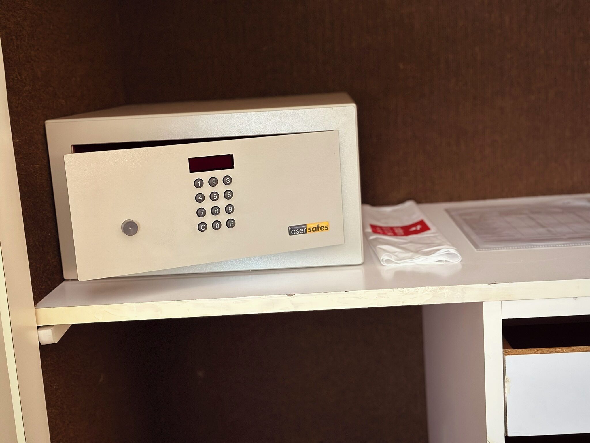 A keypad lock on a white cabinet with a brown background.