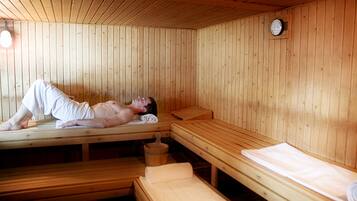 Un sauna con bancos de madera y una persona acostada en uno de ellos.
