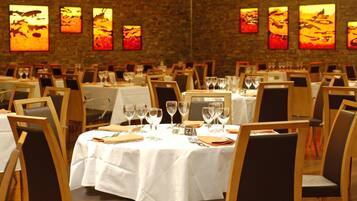 A restaurant with multiple tables set for dining, each with a white tablecloth and chairs.